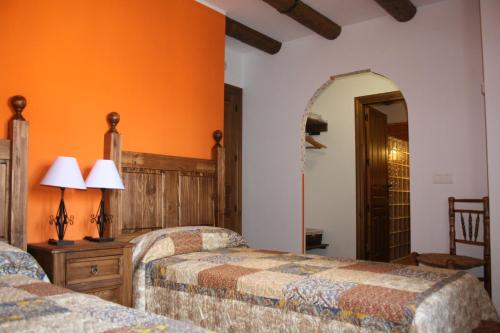 2 camas en una habitación con paredes de color naranja en La Casa del Azafrán, en Villanueva del Rebollar de la Sierra