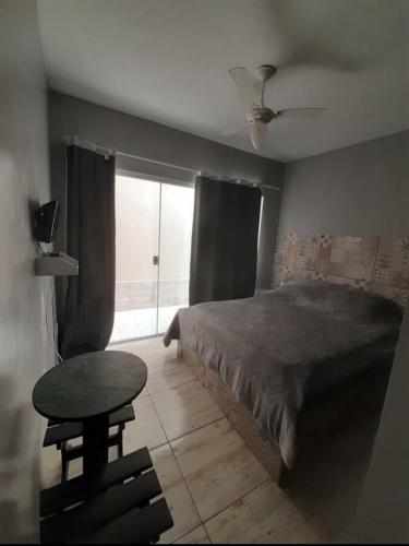 a bedroom with a bed and a table and a window at Serra Mar Suítes,Lofts, e casas à 300 metros das praias in Arraial do Cabo