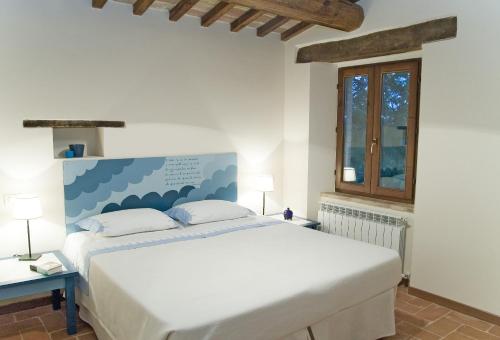 una camera da letto con un grande letto bianco e una finestra di Borgo Sorbatti a Loro Piceno