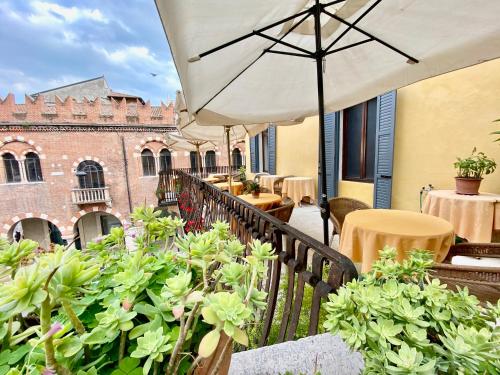 a balcony with tables and an umbrella on a building at Hotel Aurora in Verona