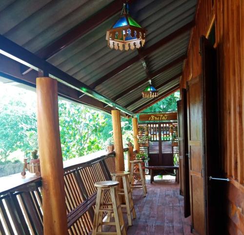 a wooden porch with stools and a chandelier at เรือนไทยใจสุขเอ๋ย in Ban Bang Wa