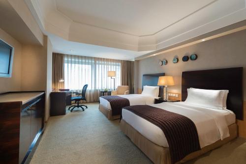 a hotel room with two beds and a desk at Marco Polo Parkside, Beijing in Beijing