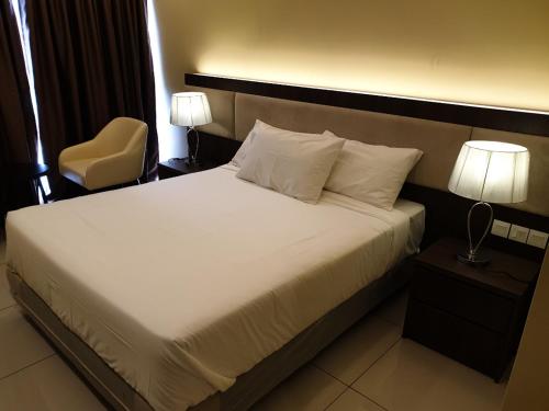 a bed in a hotel room with a chair and lamps at Studio Suite Genting Highland 33 in Genting Highlands