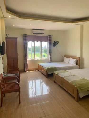 ハノイにあるNhà nghỉ Diễm Quỳnh Nội Bàiのベッドルーム1室(ベッド2台、椅子、窓付)