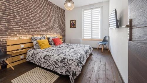Un dormitorio con una cama y una pared de ladrillo. en L'Atelier fil à fil, en Le Mans