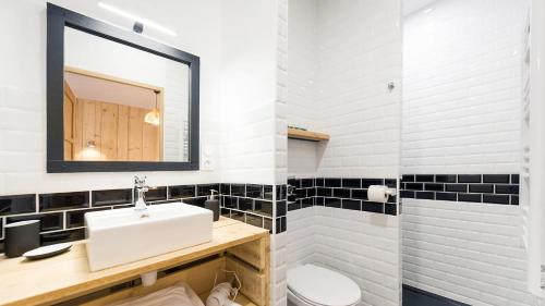 een badkamer met zwart-wit betegelde muren en een wastafel bij L'Atelier Corval in Le Mans