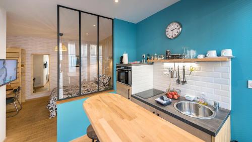 une cuisine avec un évier et une horloge murale dans l'établissement L'Atelier Corval, au Mans