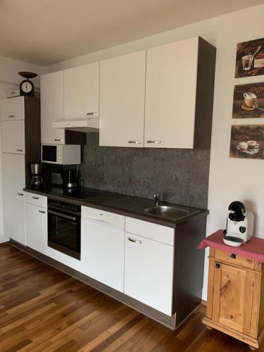 阿爾卑巴赫的住宿－Tirol Juwel，厨房配有白色橱柜和黑色台面