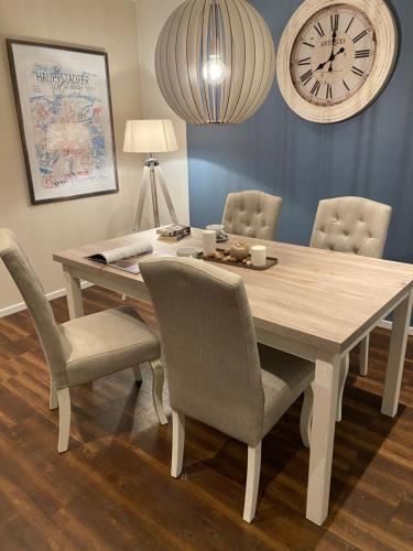 a dining room table with chairs and a clock on the wall at Family Ferienhaus Ennens in Rhauderfehn