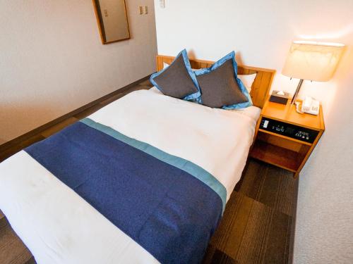 a bedroom with a bed with blue and white sheets and pillows at Hotel Area One Ise Inter in Ise