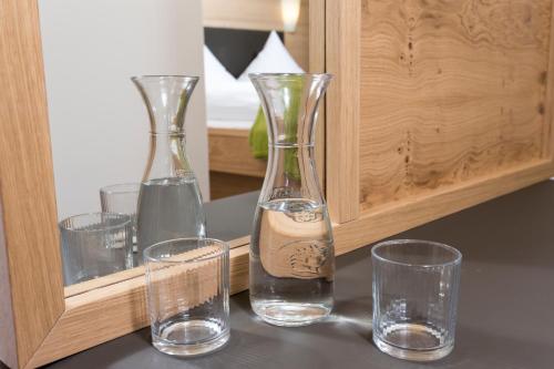 four glass vases and glasses sitting on a table at Gästehaus Mathies in Mittelberg