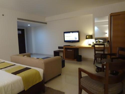 a hotel room with a bed and a desk with a television at Hotel Suba International Sahar Road Mumbai in Mumbai