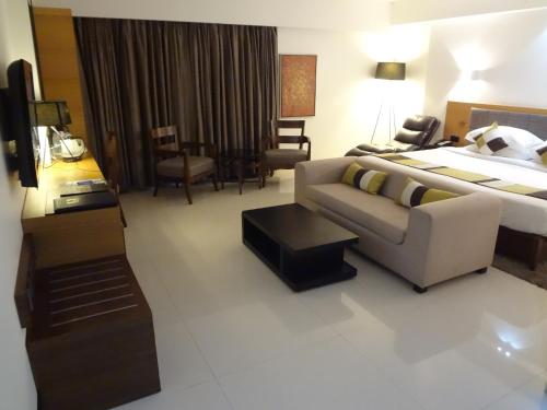 a hotel room with a couch and a bed at Hotel Suba International Sahar Road Mumbai in Mumbai