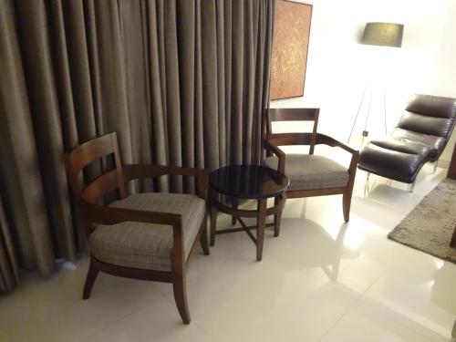 a living room with chairs and a table and curtains at Hotel Suba International Sahar Road Mumbai in Mumbai