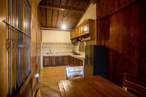 a kitchen with a wooden table and a refrigerator at Victory Munggu in Canggu