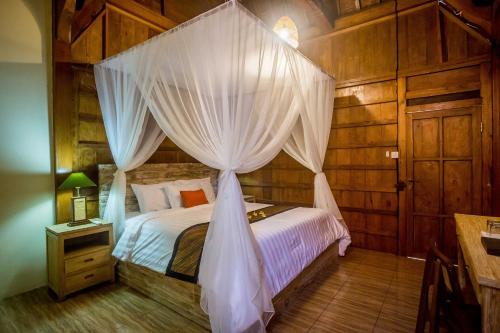a bedroom with a canopy bed with white curtains at Victory Munggu in Canggu