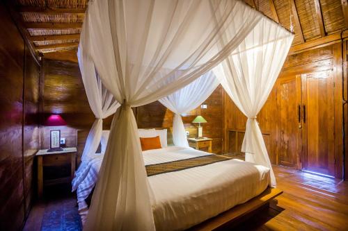 um quarto com uma cama de dossel e cortinas brancas em Victory Munggu em Canggu