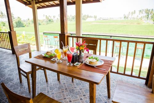 a wooden table with food and drinks on a balcony at Victory Munggu in Canggu