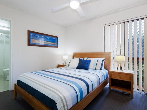 a bedroom with a large bed with blue and white sheets at Bay Parklands 57 ground floor unit with pool tennis court and aircon in Nelson Bay