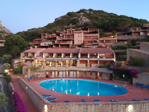 a resort with a swimming pool in front of a mountain at Hotel Olimpia in Baja Sardinia