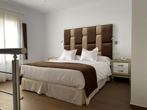 a bedroom with a large bed with a wooden headboard at Hotel boutique Palacio de la Veracruz in Alcalá la Real