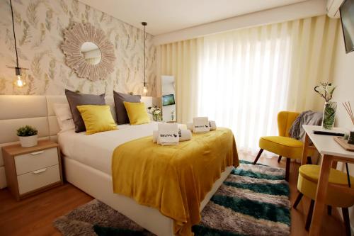 a bedroom with a large bed with yellow sheets and a desk at Bruval Premium Apartments - Gaia in Vila Nova de Gaia