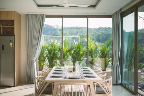 a dining room with a table and chairs and a large window at Himmapana Villas - Terraces - SHA Extra Plus in Kamala Beach