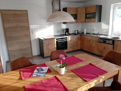 cocina con mesa de madera y servilletas rosas en Ferienwohnung Am Anger, en Amerang