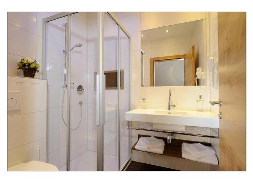 a white bathroom with a shower and a sink at Apart Garni Schadhof in Ischgl