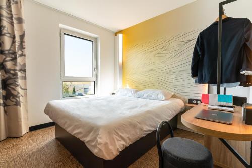 a bedroom with a bed and a desk with a laptop at B&B HOTEL Poitiers Aéroport in Poitiers