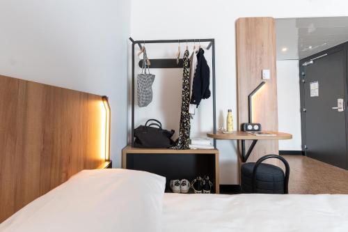 a bedroom with a bed and a closet and a table at B&B HOTEL Poitiers Aéroport in Poitiers