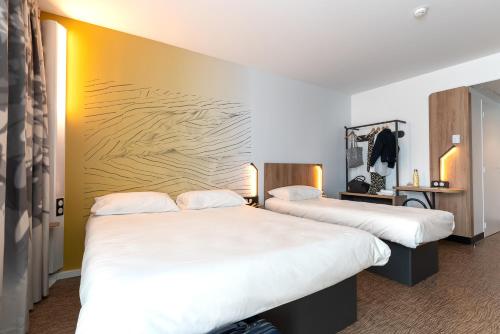 um quarto de hotel com duas camas com lençóis brancos em B&B HOTEL Poitiers Aéroport em Poitiers