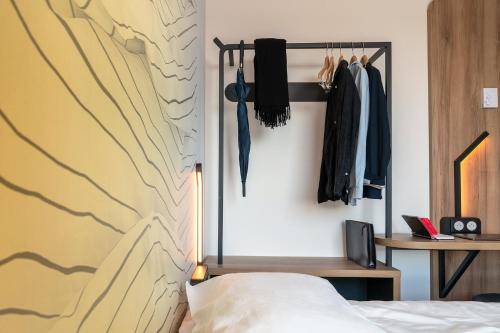 a bedroom with a bed and a wall with hanged clothes at B&B HOTEL Poitiers Aéroport in Poitiers