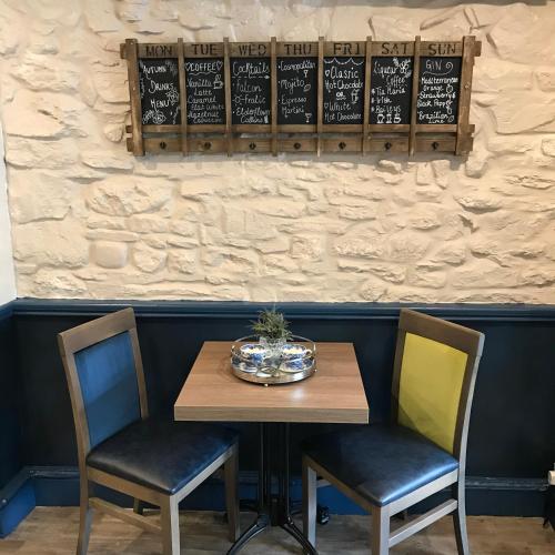a wooden table with two chairs and a menu on a wall at Falcon Hotel in Carmarthen
