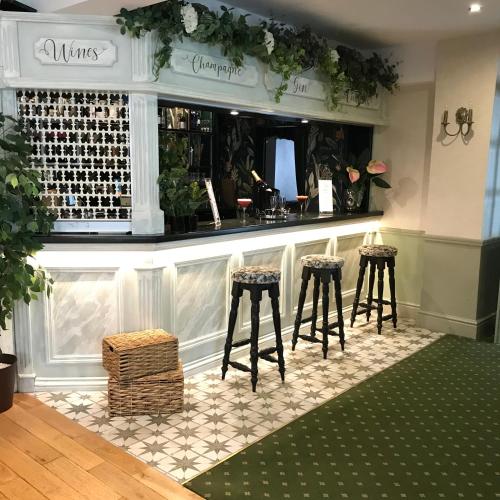 a bar with two stools and a counter with wine bottles at Falcon Hotel in Carmarthen