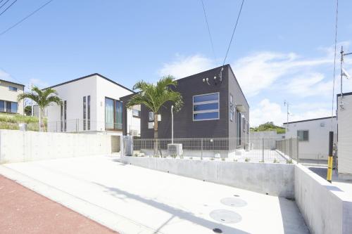 une maison noire avec une clôture et des palmiers dans l'établissement E-horizon Resort コンドミニアム名護E, à Nago