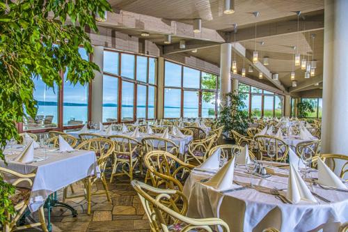 een feestzaal met tafels en stoelen en uitzicht op de oceaan bij Hotel Club Tihany in Tihany