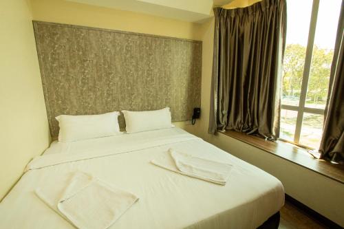 a bedroom with a white bed with two towels on it at Expo Hotel in Labuan