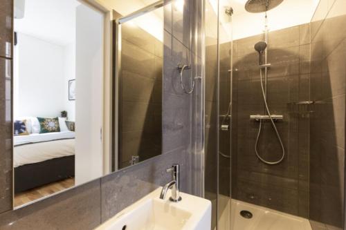 a bathroom with a shower and a sink and a mirror at Bloomsbury By Viridian Apartments in London