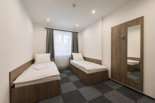 Duas camas num quarto com um espelho e um lavatório. em Hostel SMS em Bydgoszcz