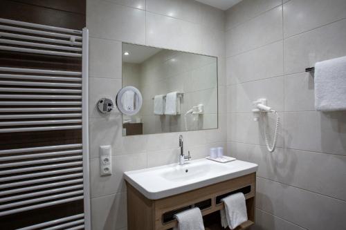a white bathroom with a sink and a mirror at Haus Hubertus in Winterspelt