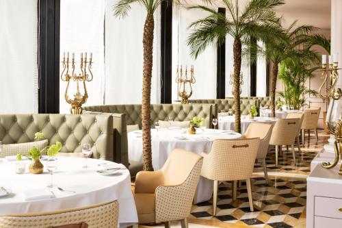 a restaurant with white tables and palm trees at Victoria Jungfrau Grand Hotel & Spa in Interlaken