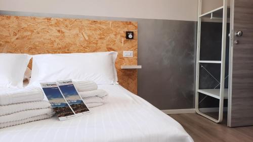 a white bed with towels and a book on it at Bergamo GuestHouse - Self Check-in in Curno