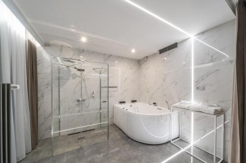 a white bathroom with a tub and a shower at Artis Loft Hotel in Radziejowice