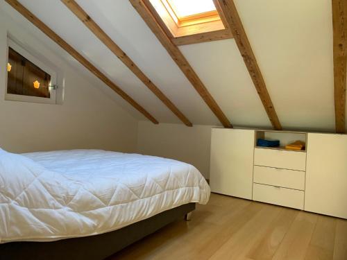 a bedroom with a white bed and a skylight at Sapin Vert in Leysin