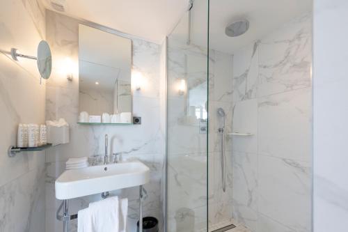 a white bathroom with a sink and a shower at Hôtel La Comtesse in Paris