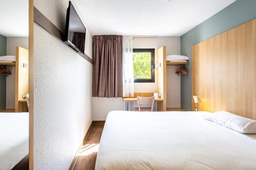 a hotel room with a bed and a desk at B&B Hôtel Angers Parc Expos in Saint-Sylvain-dʼAnjou