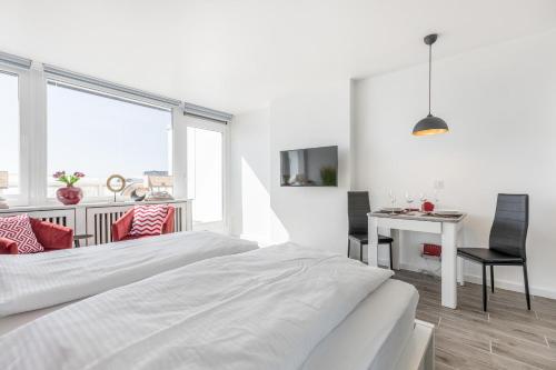 ein weißes Schlafzimmer mit einem Bett und einem Schreibtisch in der Unterkunft Ferienwohnung Penthouse in Westerland