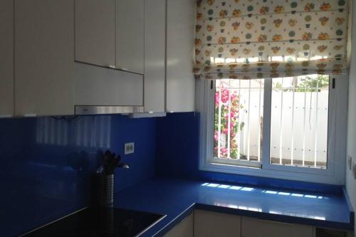 kuchnia z niebieskim blatem i oknem w obiekcie Espacioso Bungalow 2 dormitorios en Maspalomas w mieście Maspalomas