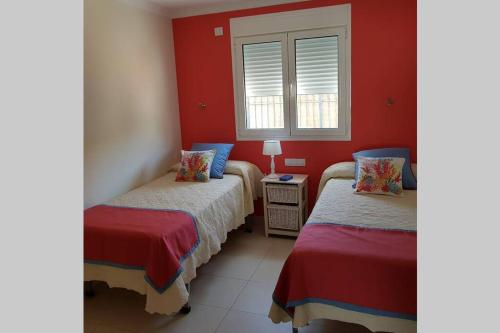 dwa łóżka w pokoju z czerwonymi ścianami w obiekcie Espacioso Bungalow 2 dormitorios en Maspalomas w mieście Maspalomas